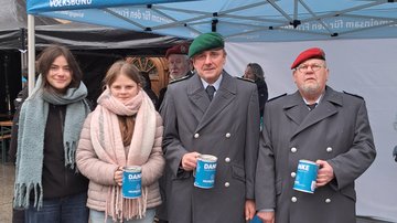 Zwei Mädchen und zwei uniformierte mit Spendendosen