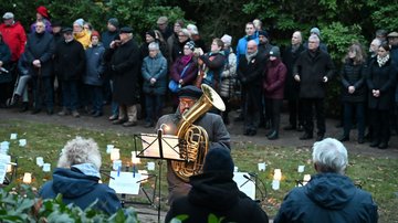 Musiker mit Blechinstrumenten. Im Hintergrund eine Gruppe Menschen.