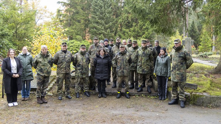 Eine Gruppe uniformierter und wenige Zivilisten blicken in die Kamera