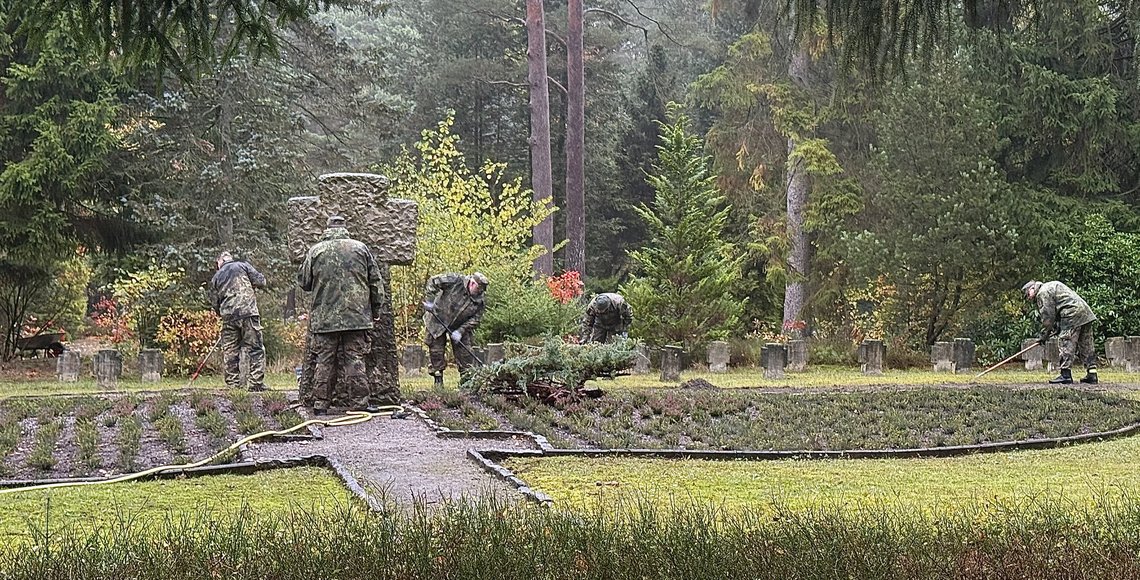 Mehrer arbeitende Personen in Uniform auf einem Friedhof
